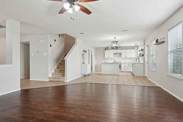 6128 Redear Dr, Fort Worth, TX 76179 - unfurnished living room with light wood-type flooring, a ceiling fan, a chandelier, and a sink