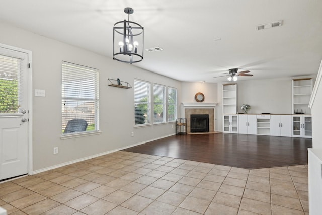 6128 Redear Dr, Fort Worth, TX 76179 - unfurnished living room with light tile patterned floors, ceiling fan, a tiled fireplace, built in features, and a chandelier
