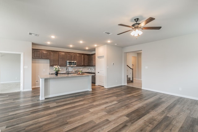 2028 Proteus Dr, Haslet, TX 76052 - kitchen with stainless steel microwave, a ceiling fan, dark brown cabinets, decorative backsplash, and baseboards