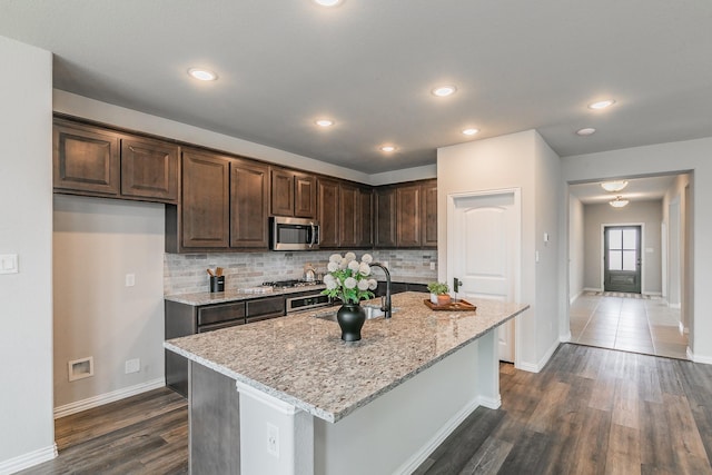 2028 Proteus Dr, Haslet, TX 76052 - kitchen with appliances with stainless steel finishes, dark wood-style flooring, a sink, light stone counters, and tasteful backsplash