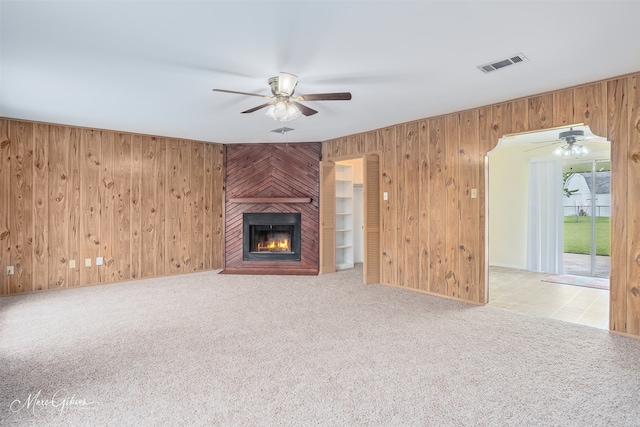 3425 Ponderosa Dr, Bossier City, LA 71112 - unfurnished living room with a ceiling fan, wood walls, a fireplace, and carpet floors