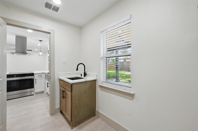 2614 E Mitchell St, Arlington, TX 76010 - kitchen featuring stainless steel electric range, a sink, island range hood, light wood-style flooring, and light countertops