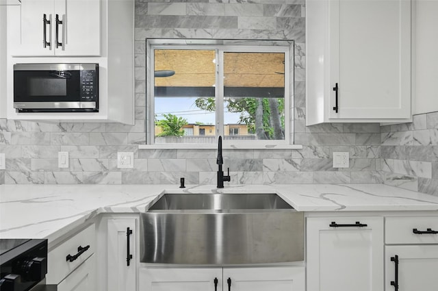 2614 E Mitchell St, Arlington, TX 76010 - kitchen featuring stainless steel microwave, a sink, decorative backsplash, and white cabinetry