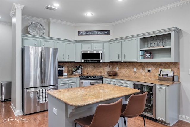 9406 Prestonwood Cir, Shreveport, LA 71115 - kitchen featuring appliances with stainless steel finishes, wine cooler, ornamental molding, light wood finished floors, and a kitchen bar
