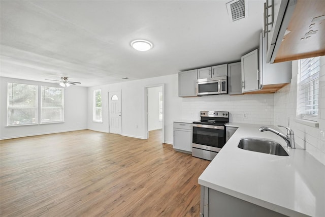 210 N 5th Ave, Denison, TX 75021 - kitchen featuring stainless steel appliances, a sink, light countertops, decorative backsplash, and gray cabinetry