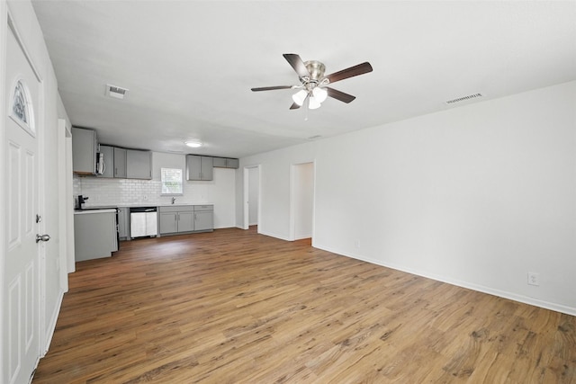 210 N 5th Ave, Denison, TX 75021 - unfurnished living room featuring ceiling fan, wood finished floors, a sink, and baseboards