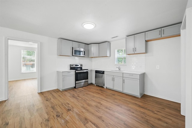 210 N 5th Ave, Denison, TX 75021 - kitchen featuring appliances with stainless steel finishes, a sink, gray cabinets, and light wood finished floors