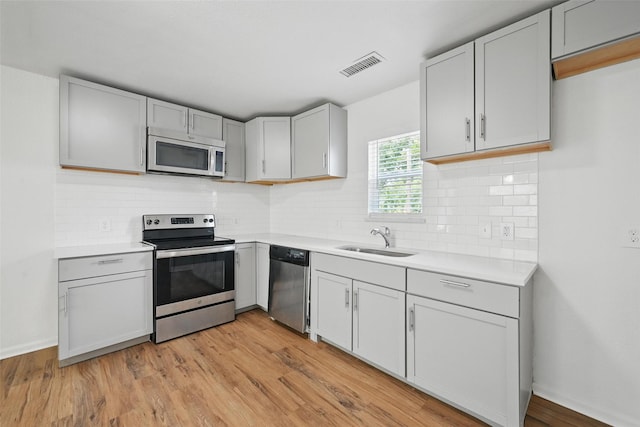 210 N 5th Ave, Denison, TX 75021 - kitchen featuring stainless steel appliances, a sink, light countertops, and light wood-style flooring