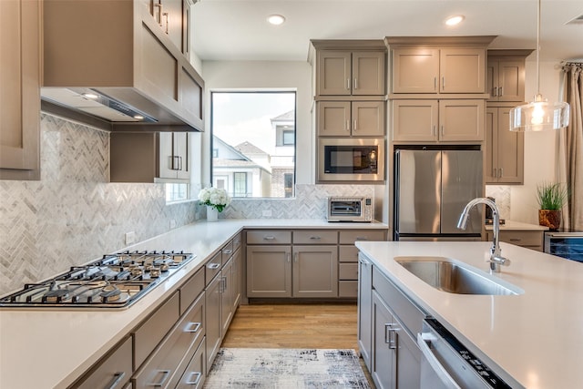 8120 Radnor Rd, Dallas, TX 75231 - kitchen with stainless steel appliances, light countertops, a sink, ventilation hood, and light wood finished floors