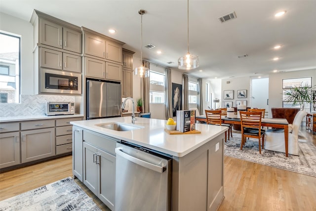8120 Radnor Rd, Dallas, TX 75231 - kitchen with appliances with stainless steel finishes, gray cabinetry, a sink, light wood finished floors, and recessed lighting