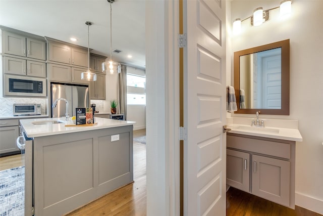 8120 Radnor Rd, Dallas, TX 75231 - kitchen with gray cabinets, stainless steel fridge, built in microwave, a sink, and light wood finished floors