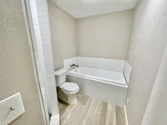 12331 Ferris Creek Ln, Dallas, TX 75243 - full bath with a textured wall, wood finished floors, toilet, a bath, and a textured ceiling