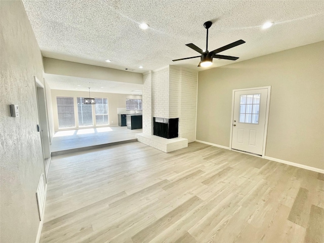 12331 Ferris Creek Ln, Dallas, TX 75243 - unfurnished living room featuring a ceiling fan, light wood finished floors, a textured ceiling, baseboards, and a fireplace