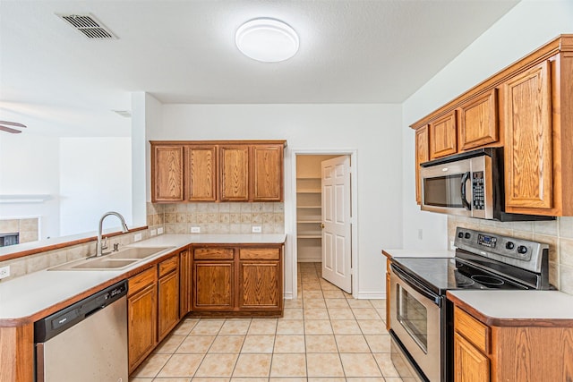 1301 Hennessey Ct, Fort Worth, TX 76131 - kitchen with stainless steel appliances, a sink, backsplash, and brown cabinetry