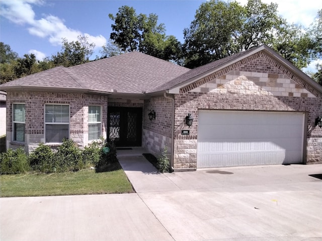 899 E Jefferson St, Van Alstyne, TX 75495 - view of front of house featuring a garage, stone siding, roof with shingles, brick siding, and concrete driveway