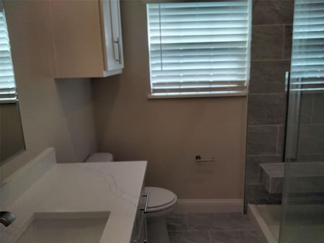 899 E Jefferson St, Van Alstyne, TX 75495 - bathroom featuring toilet, a stall shower, vanity, marble finish floors, and baseboards