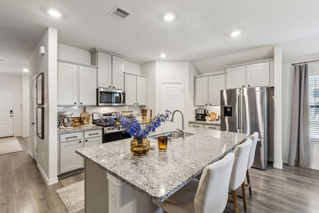 1104 Egret Way, Celina, TX 75009 - kitchen with appliances with stainless steel finishes, a sink, a kitchen breakfast bar, wood finished floors, and baseboards