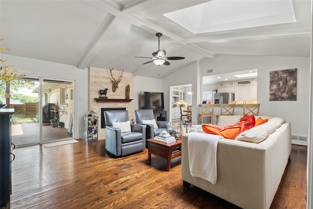 10420 Carry Back Cir, Dallas, TX 75229 - living room featuring wood finished floors, beamed ceiling, a stone fireplace, a ceiling fan, and a skylight