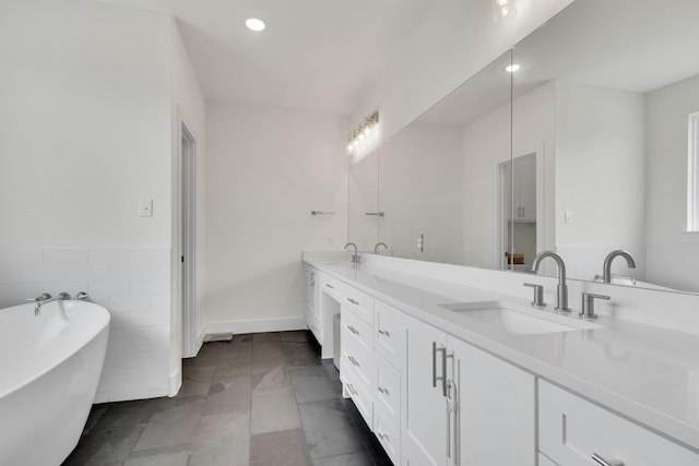 219 Mulkey Rd, Waxahachie, TX 75167 - bathroom with double vanity, a soaking tub, recessed lighting, tile walls, and wainscoting