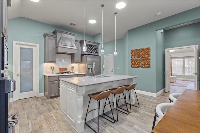 800 Marion Farm Rd E, Little Elm, TX 75068 - kitchen featuring stainless steel appliances, premium range hood, a sink, light countertops, and light wood-style floors