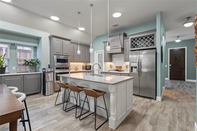 800 Marion Farm Rd E, Little Elm, TX 75068 - kitchen with stainless steel appliances, a sink, custom exhaust hood, gray cabinetry, and light wood finished floors