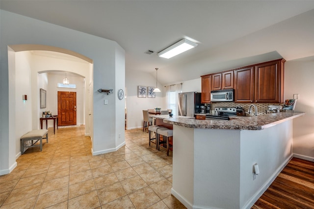 2813 Ashton Way, Mckinney, TX 75071 - kitchen with appliances with stainless steel finishes, a kitchen breakfast bar, arched walkways, backsplash, and a peninsula