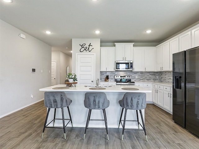 3019 Dakota Trl, Crandall, TX 75114 - kitchen with stainless steel appliances, a sink, light wood finished floors, a kitchen island with sink, and a kitchen breakfast bar