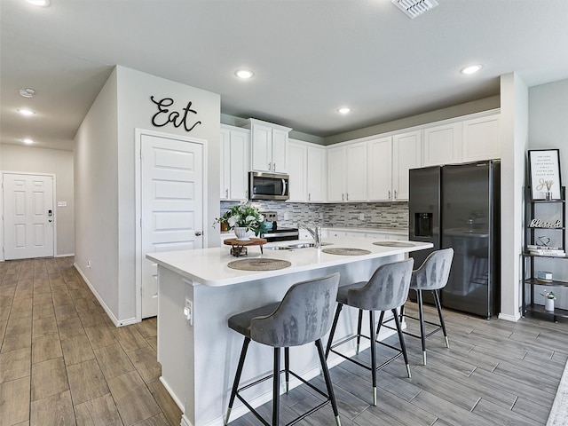 3019 Dakota Trl, Crandall, TX 75114 - kitchen featuring refrigerator with ice dispenser, stainless steel microwave, light wood-style flooring, white cabinetry, and recessed lighting