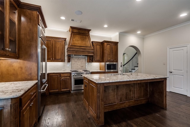 901 Drummond Dr, Prosper, TX 75078 - kitchen with high quality appliances, ornamental molding, dark wood-style floors, arched walkways, and a kitchen island with sink