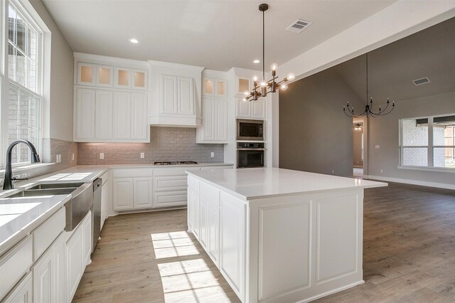 604 Bluff Point Ln, Haslet, TX 76052 - kitchen with a chandelier, appliances with stainless steel finishes, decorative backsplash, light wood-style floors, and a center island