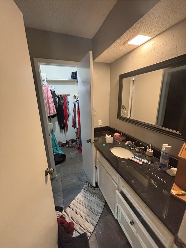 701 Rocky Canyon Rd, Arlington, TX 76012 - bathroom featuring vanity, a textured ceiling, and a spacious closet