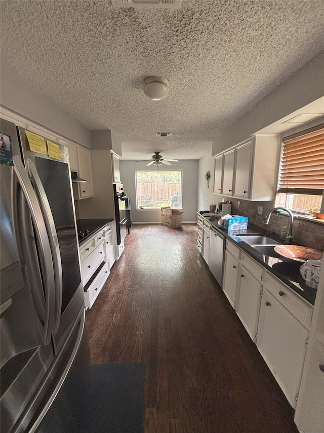 701 Rocky Canyon Rd, Arlington, TX 76012 - kitchen featuring appliances with stainless steel finishes, dark wood-style flooring, white cabinets, dark countertops, and a textured ceiling