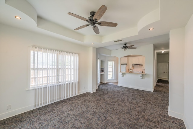 101 S Walnut St, Petrolia, TX 76377 - unfurnished living room featuring ceiling fan, carpet flooring, a tray ceiling, recessed lighting, and arched walkways