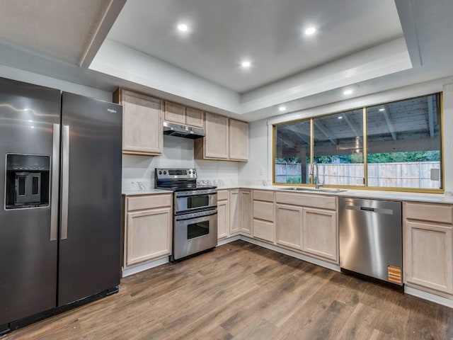 3101 Oak Hill Rd, Carrollton, TX 75007 - kitchen featuring appliances with stainless steel finishes, a sink, under cabinet range hood, light brown cabinetry, and dark wood-style floors