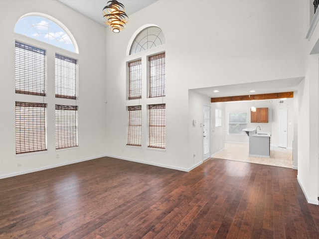 4688 Thanksgiving Ln, Plano, TX 75024 - unfurnished living room with dark wood-style floors, baseboards, a towering ceiling, and a sink