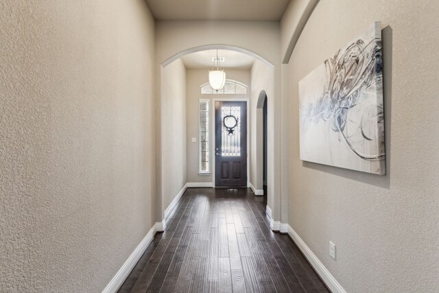 1117 Summer Ln, Mckinney, TX 75071 - foyer with arched walkways, a textured wall, dark wood-type flooring, and baseboards
