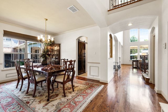 1765 Mustang Trl, Frisco, TX 75033 - dining space with a barn door, arched walkways, wood finished floors, a chandelier, and ornamental molding