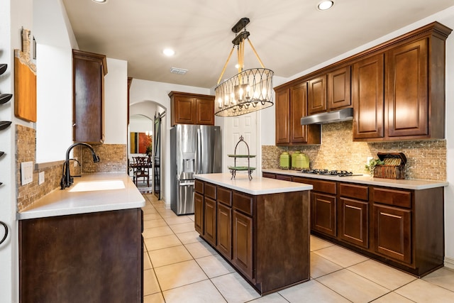 1765 Mustang Trl, Frisco, TX 75033 - kitchen featuring a sink, stainless steel refrigerator with ice dispenser, under cabinet range hood, arched walkways, and tasteful backsplash