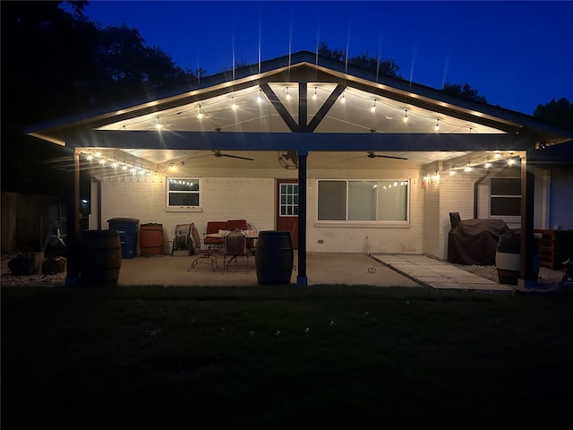 12305 Sunland St, Dallas, TX 75218 - back of house at night featuring ceiling fan, a patio, and brick siding
