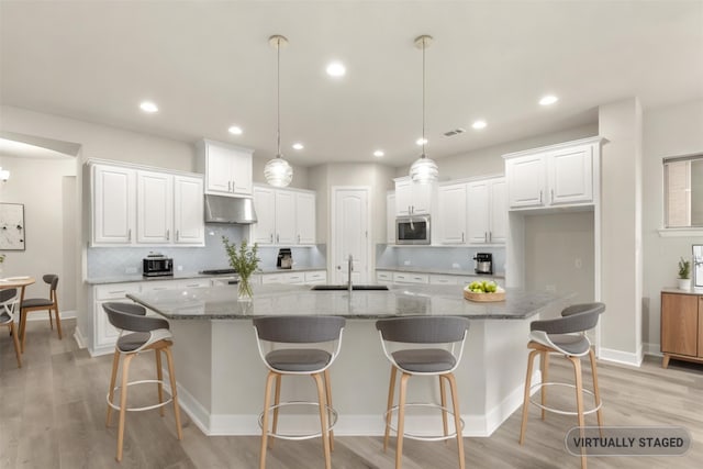 1725 Rolling Heights Ln, Fort Worth, TX 76008 - kitchen with stainless steel microwave, under cabinet range hood, white cabinets, a sink, and recessed lighting