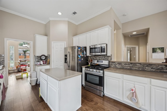 4077 Truman Dr, Frisco, TX 75034 - kitchen featuring appliances with stainless steel finishes, decorative backsplash, white cabinets, crown molding, and a center island