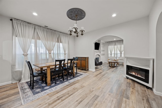 3208 Travis Ave, Fort Worth, TX 76110 - dining space featuring a glass covered fireplace, arched walkways, healthy amount of natural light, light wood-type flooring, and recessed lighting
