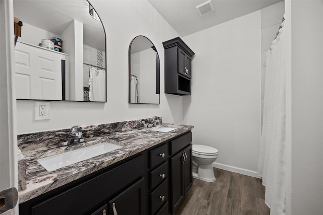 3208 Travis Ave, Fort Worth, TX 76110 - bathroom featuring double vanity, toilet, wood finished floors, a shower with curtain, and baseboards