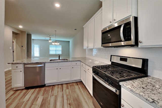 2117 Jeanine Dr, Anna, TX 75409 - kitchen featuring appliances with stainless steel finishes, a sink, light wood finished floors, a peninsula, and white cabinets