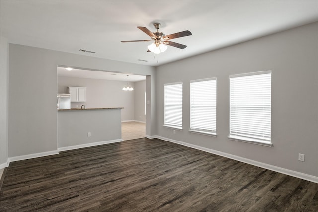 134 Kennedy Dr, Venus, TX 76084 - unfurnished living room featuring a ceiling fan, a chandelier, dark wood-type flooring, and baseboards