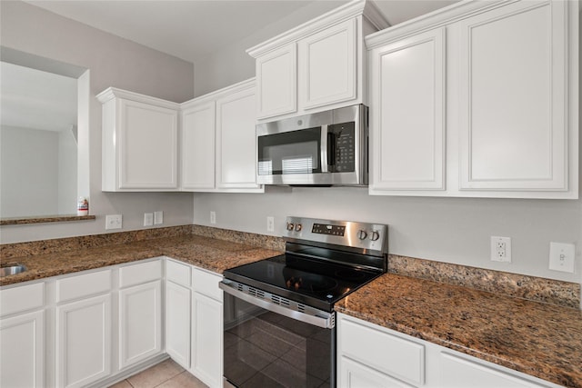 134 Kennedy Dr, Venus, TX 76084 - kitchen featuring appliances with stainless steel finishes, dark stone countertops, white cabinetry, and light tile patterned floors