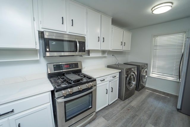704 Vine St, Euless, TX 76040 - kitchen featuring appliances with stainless steel finishes, washing machine and dryer, wood finished floors, white cabinetry, and baseboards