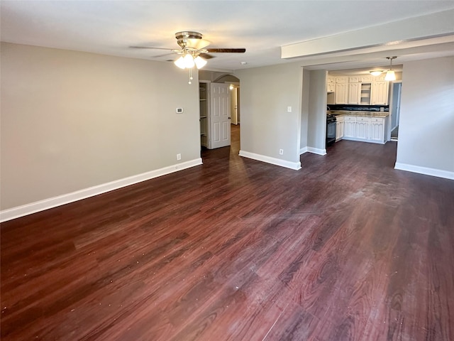 5729 Blackmore Ave, Fort Worth, TX 76107 - unfurnished living room with a ceiling fan, baseboards, dark wood-type flooring, and arched walkways