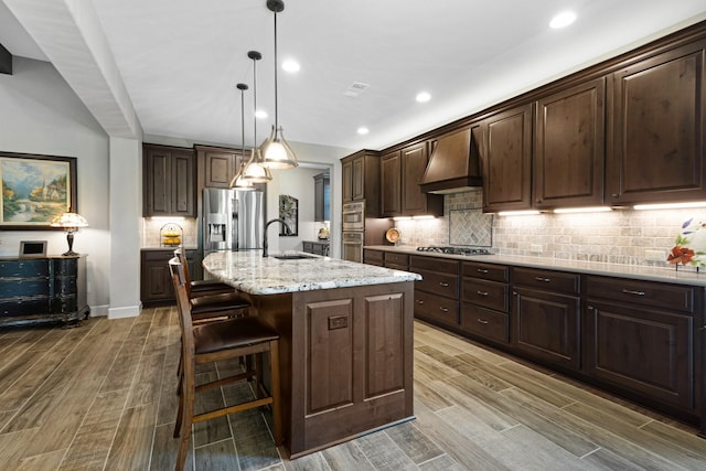 8217 American Way, Denton, TX 76207 - kitchen with premium range hood, a sink, wood finished floors, tasteful backsplash, and dark brown cabinets