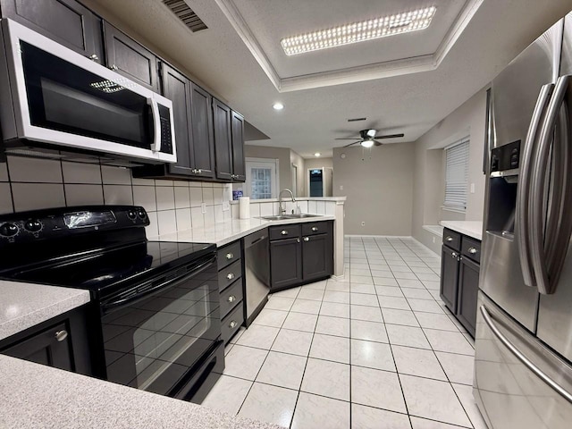1001 Schrade Trl, Mesquite, TX 75181 - kitchen featuring appliances with stainless steel finishes, a sink, a peninsula, a tray ceiling, and a ceiling fan
